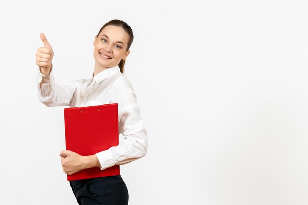 Vista frontale giovane donna in camicetta bianca con file rosso nelle sue mani sorridente su sfondo bianco lavoro d'ufficio emozione femminile modello di sentimento
