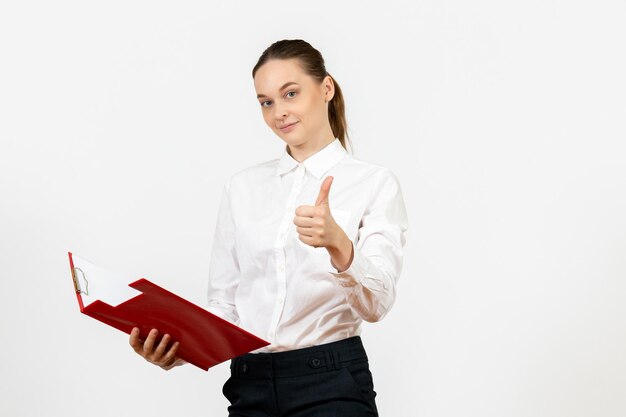 Vista frontale giovane donna in camicetta bianca con file rosso sul pavimento bianco ufficio emozione femminile sentimento modello lavoro