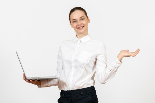 Vista frontale giovane donna in camicetta bianca utilizzando laptop e sorridente su sfondo bianco lavoro ufficio sensazione femminile modello emozione