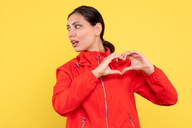 Vista frontale giovane donna in cappotto rosso su sfondo giallo