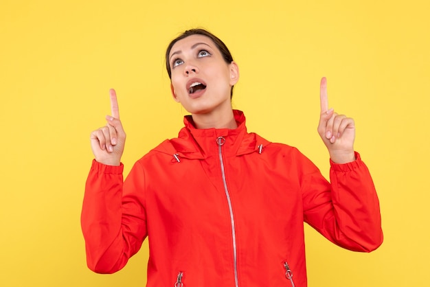 Vista frontale giovane donna in cappotto rosso su sfondo giallo