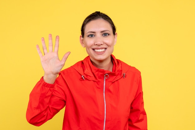 Vista frontale giovane donna in cappotto rosso su sfondo giallo