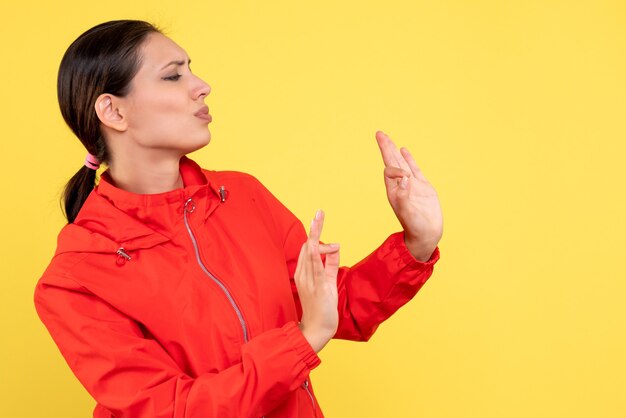 Vista frontale giovane donna in cappotto rosso su sfondo giallo