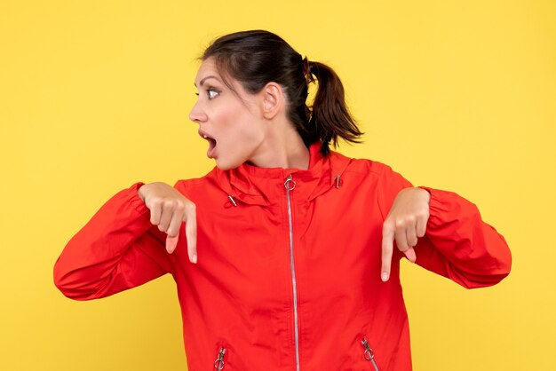 Vista frontale giovane donna in cappotto rosso su sfondo giallo