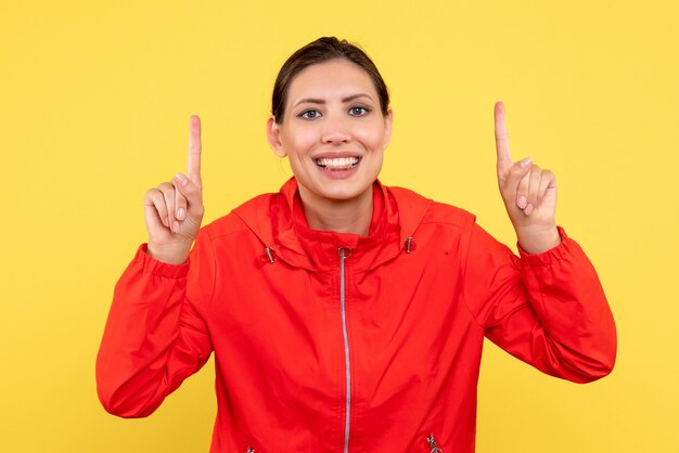 Vista frontale giovane donna in cappotto rosso su sfondo giallo