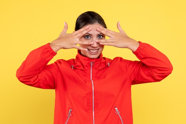 Vista frontale giovane donna in cappotto rosso su sfondo giallo