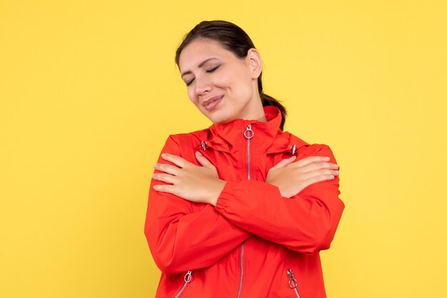 Vista frontale giovane donna in cappotto rosso su sfondo giallo