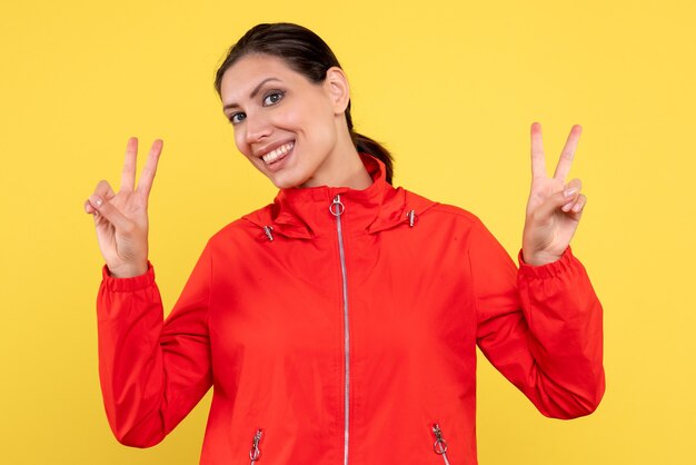 Vista frontale giovane donna in cappotto rosso su sfondo giallo