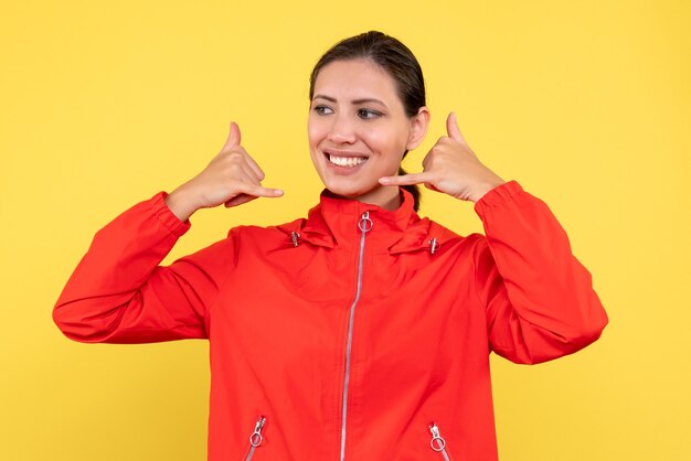 Vista frontale giovane donna in cappotto rosso su sfondo giallo