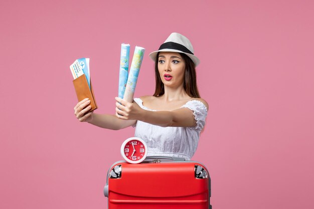 Vista frontale giovane donna in possesso di biglietti e mappa in vacanza sulla parete rosa calore vacanza viaggio donna viaggio estate