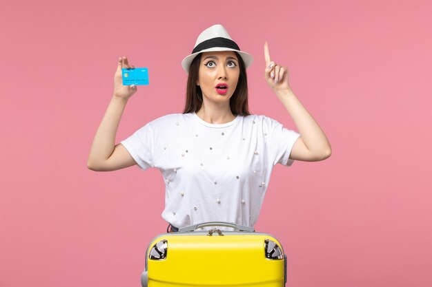 Vista frontale giovane donna in possesso di carta di credito sul muro rosa viaggio donna emozioni estive
