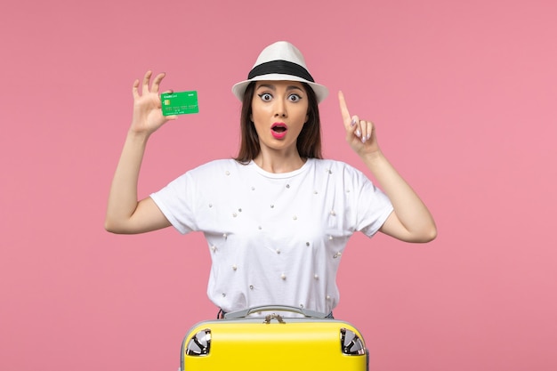 Vista frontale giovane donna in possesso di carta di credito sulla scrivania rosa emozione estate donna viaggio