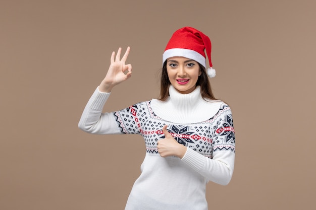 Vista frontale giovane donna sorridente con tappo rosso su sfondo marrone emozione natale capodanno