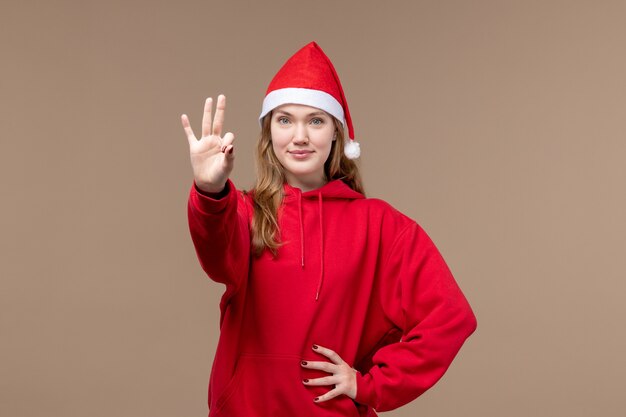 Vista frontale giovane femmina che mostra numero su sfondo marrone emozione vacanze di Natale