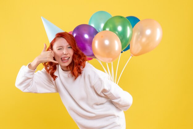 Vista frontale giovane femmina che nasconde palloncini colorati dietro la schiena colore