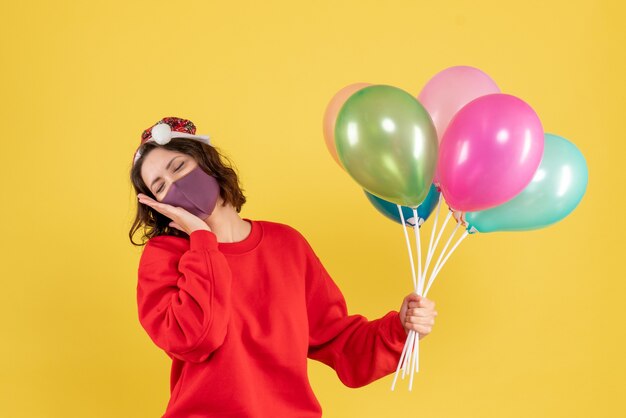 Vista frontale giovane femmina che tiene palloncini in maschera sterile su giallo