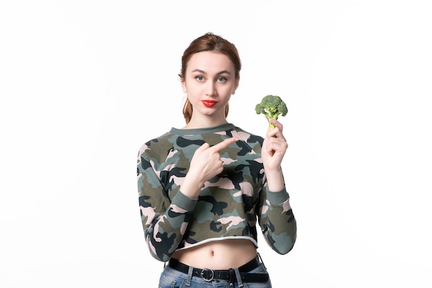 Vista frontale giovane femmina con broccoli verdi su sfondo bianco pranzo corpo orizzontale pasto insalata cibo dieta salute piatto