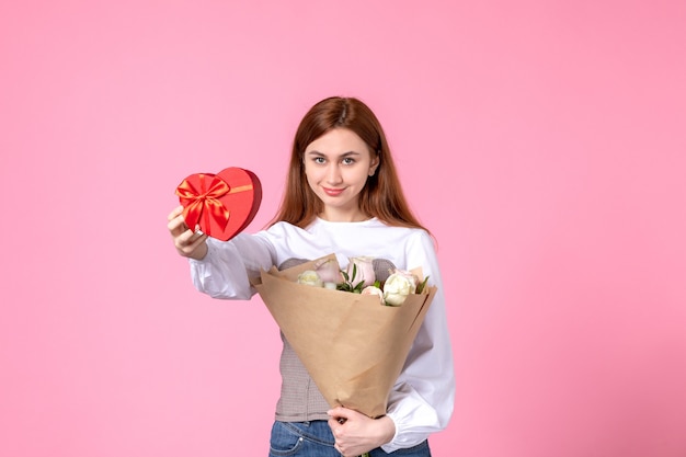 Vista frontale giovane femmina con fiori e presente come regalo di giorno delle donne su sfondo rosa parità di marcia orizzontale amore sensuale data femminile rosa