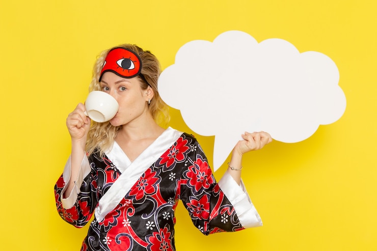Foto gratuito vista frontale giovane femmina in abito da notte con un enorme cartello bianco e bere caffè sul muro giallo dormire notte letto modello colore