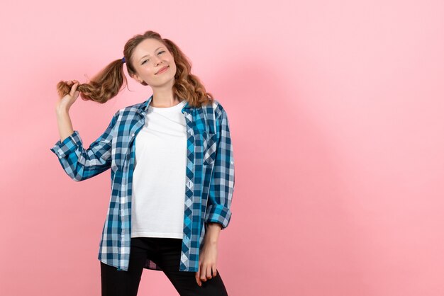 Vista frontale giovane femmina in camicia a scacchi blu in posa con il sorriso su sfondo rosa donna emozioni ragazze moda modello di colore