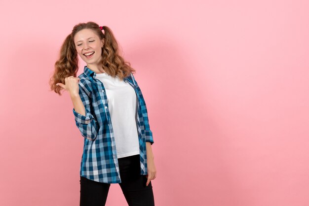 Vista frontale giovane femmina in camicia a scacchi blu in posa su sfondo rosa kid gioventù emozione modello moda donna colore