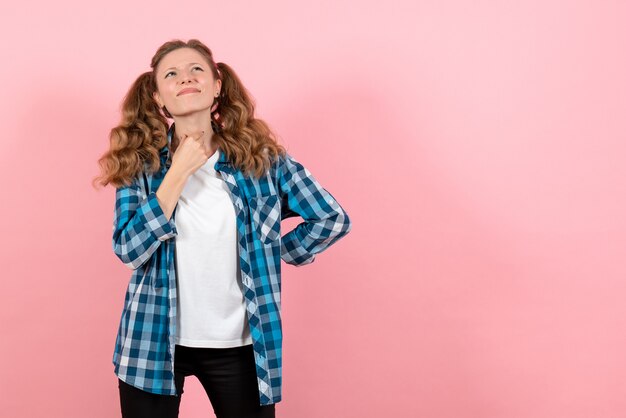 Vista frontale giovane femmina in camicia a scacchi blu in posa su sfondo rosa ragazza gioventù emozione modello moda bambino