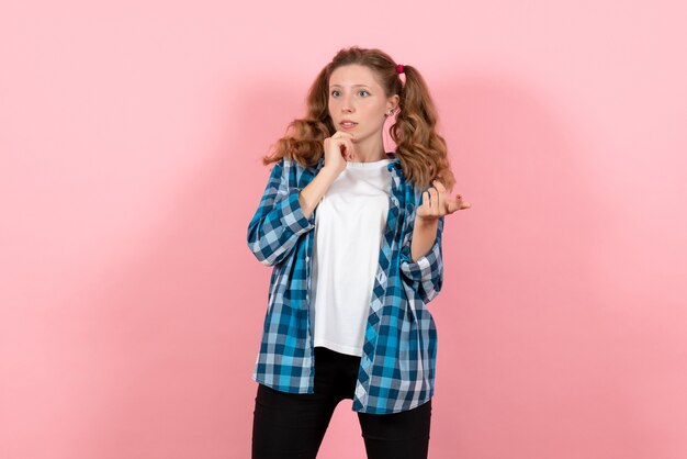 Vista frontale giovane femmina in camicia a scacchi blu in posa su uno sfondo rosa emozioni giovanili ragazza modello moda bambino