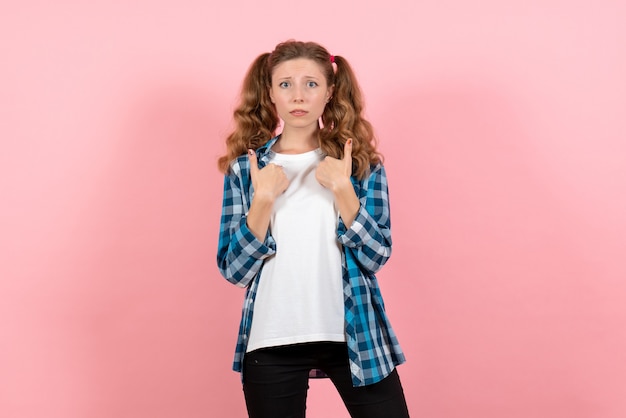 Vista frontale giovane femmina in camicia a scacchi in posa sullo sfondo rosa modello emozioni ragazzino gioventù donna ragazza