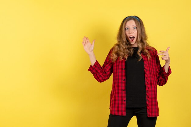 Vista frontale giovane femmina in camicia a scacchi rossa in posa su sfondo giallo modello ragazze donna colore emozione umana