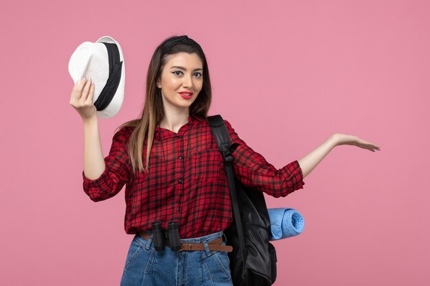 Vista frontale giovane femmina in camicia rossa con cappello su sfondo rosa chiaro donna di colore umano