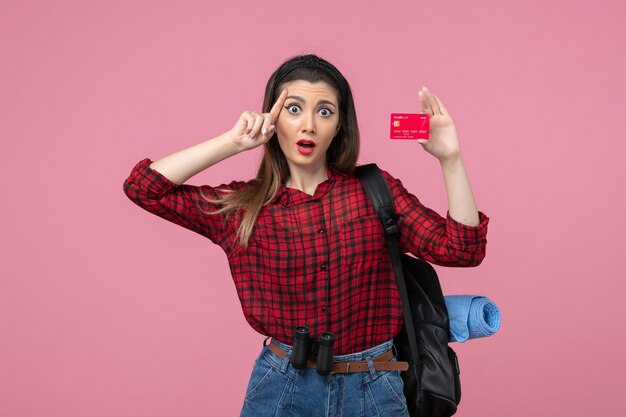 Vista frontale giovane femmina in camicia rossa con carta di credito su sfondo rosa donna umana colori