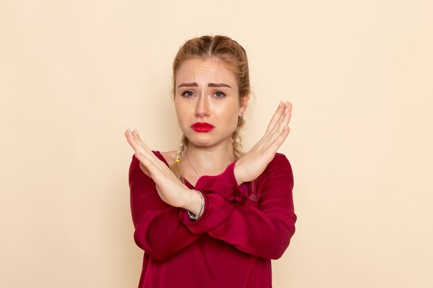 Vista frontale giovane femmina in camicia rossa shwoign segno di divieto piangendo sulla crema spazio femmina panno foto