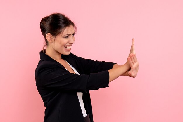 Vista frontale giovane femmina in giacca scura su sfondo rosa