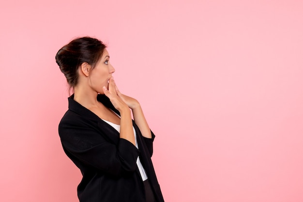 Vista frontale giovane femmina in giacca scura su sfondo rosa