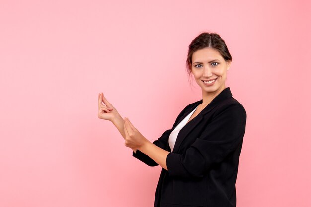 Vista frontale giovane femmina in giacca scura su sfondo rosa