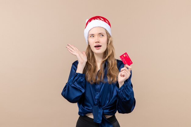 Vista frontale giovane femmina in possesso di carta di credito rossa su sfondo rosa soldi foto vacanza capodanno natale emozione