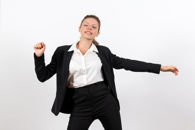 Vista frontale giovane femmina in rigoroso abito classico e sbadigliando su sfondo bianco lavoro donna tailleur lavoro femminile