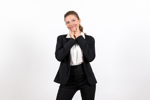 Vista frontale giovane femmina in rigoroso abito classico in posa su uno sfondo bianco lavoro affari lavoro donna vestito femminile