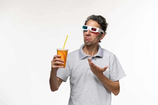 Vista frontale giovane maschio bere soda e indossare occhiali da sole d su superficie bianca