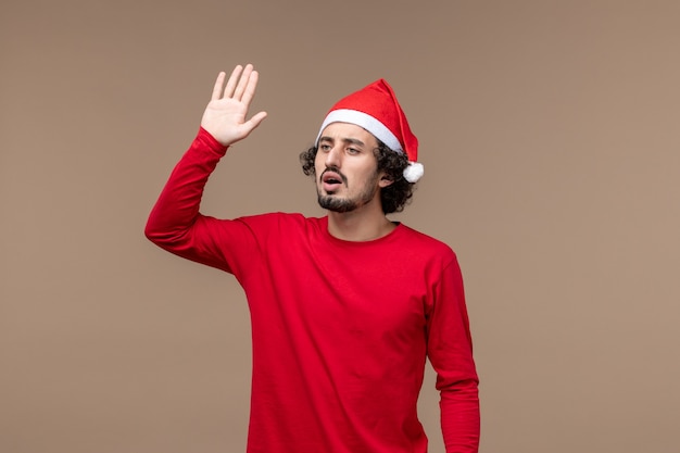 Vista frontale giovane maschio che fluttua su uno sfondo marrone emozioni vacanze di Natale