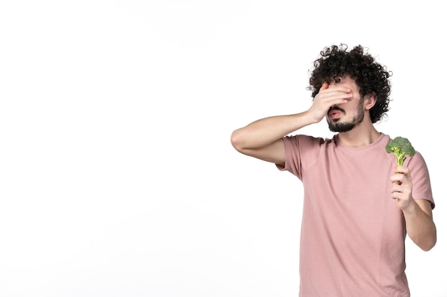 Vista frontale giovane maschio che tiene piccoli broccoli su sfondo bianco insalata dieta orizzontale peso vegetale salute corpo umano