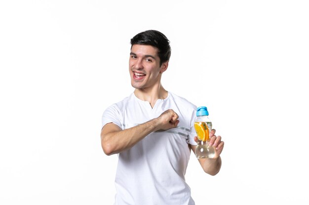 Vista frontale giovane maschio che tiene una bottiglia di limonata su bianco
