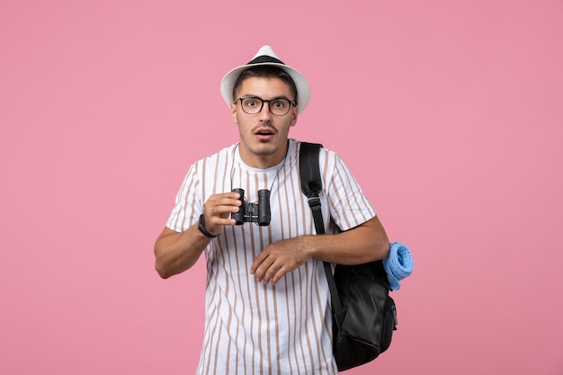 Vista frontale giovane maschio con borsa e binocolo su sfondo rosa chiaro