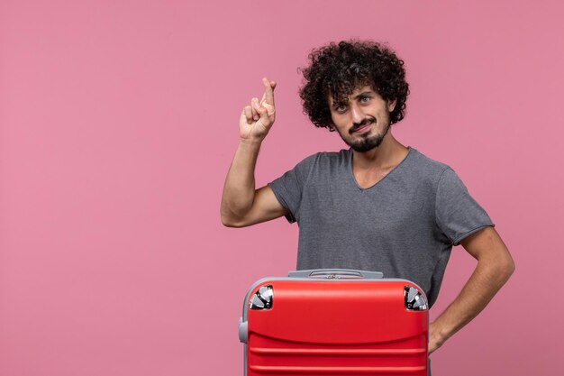 Vista frontale giovane maschio con borsa rossa su spazio rosa chiaro