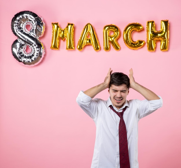 Vista frontale giovane maschio con decorazione di marzo su sfondo rosa colore matrimonio femminile marito uguaglianza festa della donna festa uomo presente