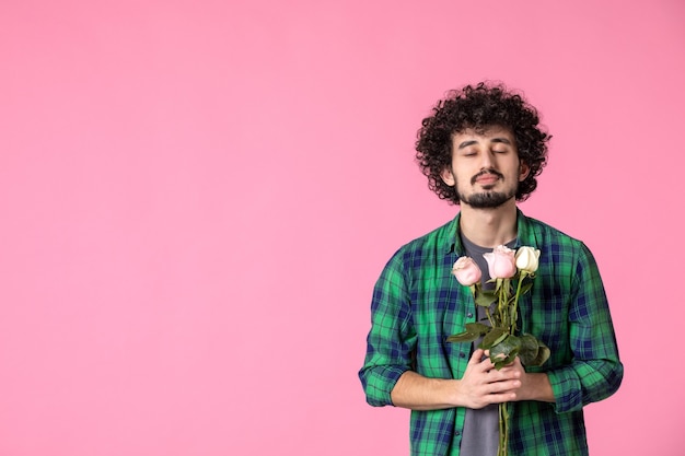 Vista frontale giovane maschio con rose rosa su colore rosa