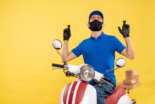 Vista frontale giovane maschio corriere in bicicletta in maschera su sfondo giallo