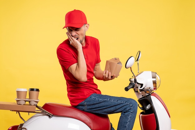 Vista frontale giovane maschio corriere in uniforme rossa che soffre di mal di denti su sfondo giallo