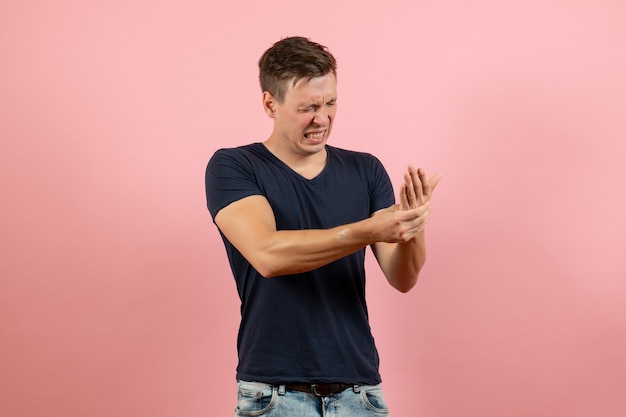 Vista frontale giovane maschio in camicia blu scuro ferito il braccio su sfondo rosa maschio modello umano colore emozione uomo