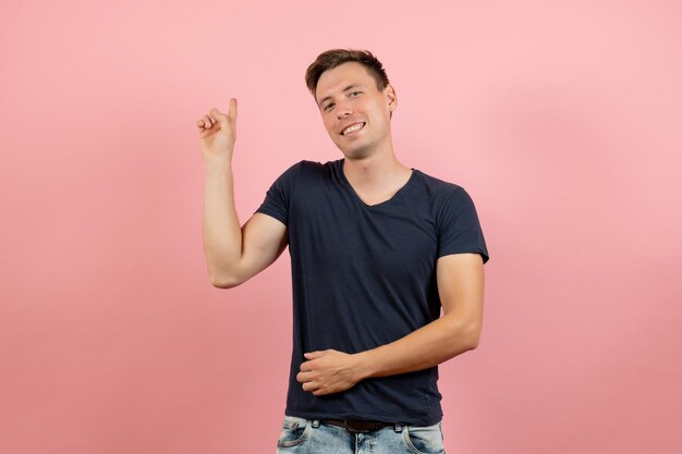 Vista frontale giovane maschio in camicia blu scuro in posa con un sorriso su sfondo rosa